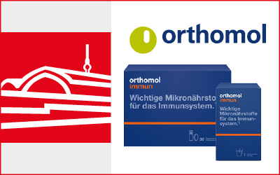 Das rote Icon der Aschenbachs Apotheke am Bahnhof Friedrichstraße. Rechts daneben stehen Produkte von orthomol mit dem Logo darüber